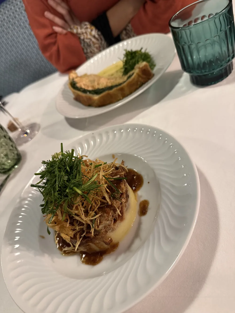 Viande effilochée sur une purée, couronnée de fines herbes et de pommes de terre en filaments