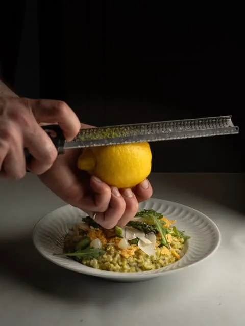 Citron râpé au-dessus d'une assiette de risotto aux herbes